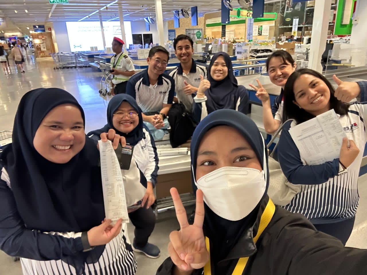 Group selfie at the checkout holding up the receipts