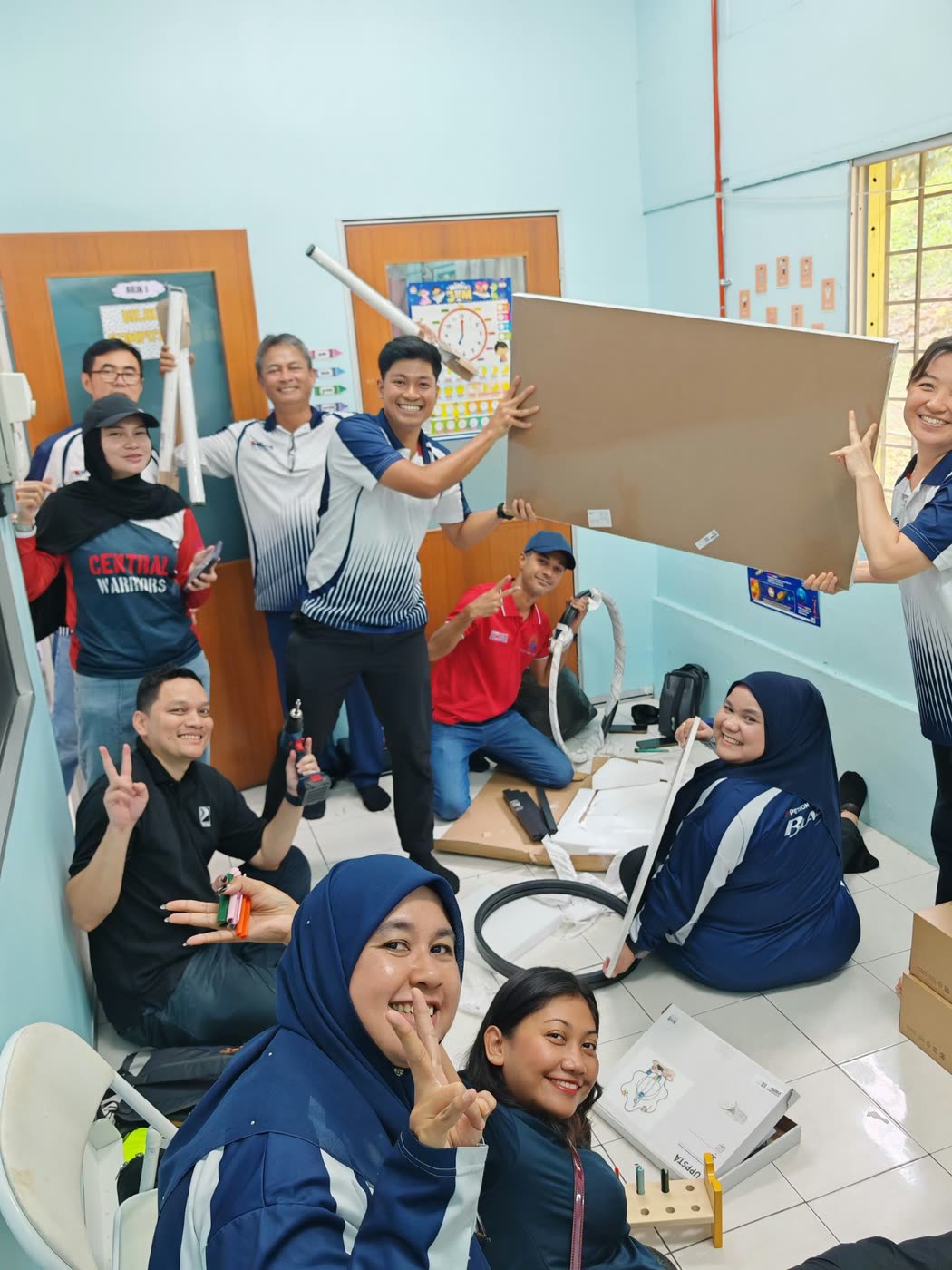 A cheerful group in the classroom holding up panels and tools mid-assembly