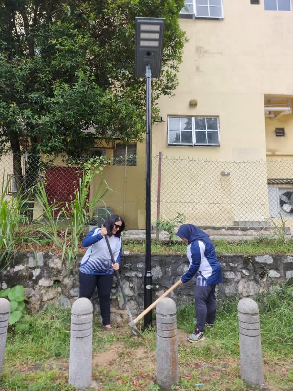 Two committee members backfilling soil around a newly installed solar light pole