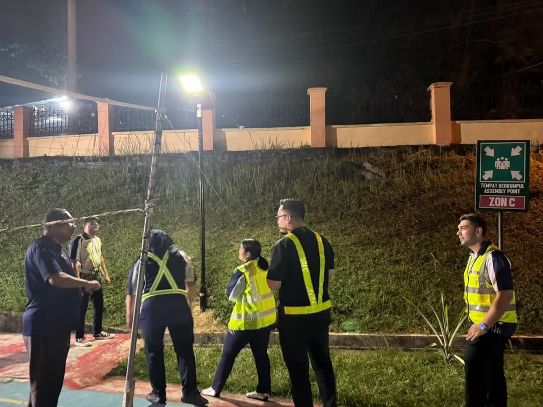 Team in safety vests checking a lit solar light by the slope at night